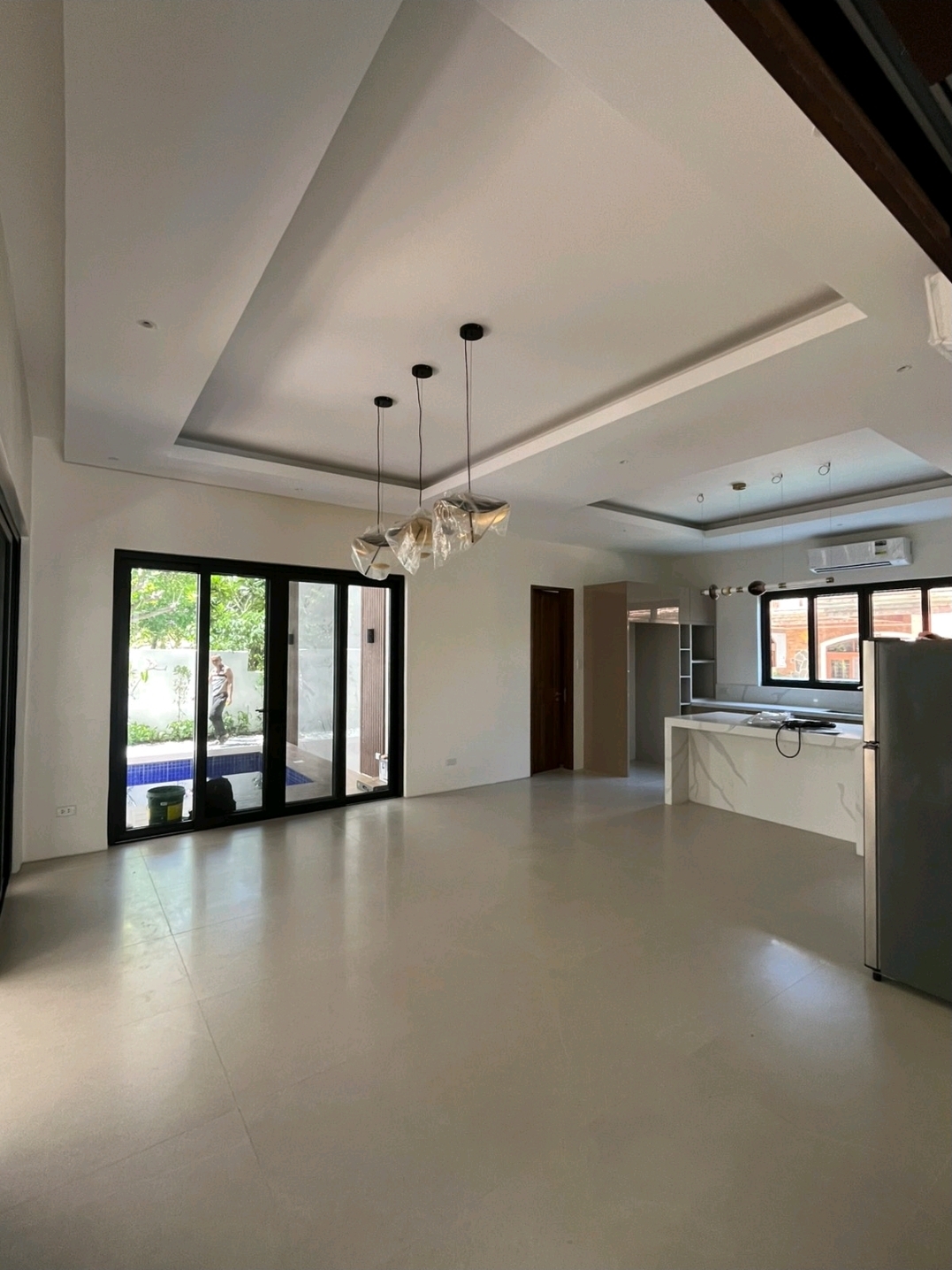 Open living and dining area with cove ceiling and glass doors to the pool