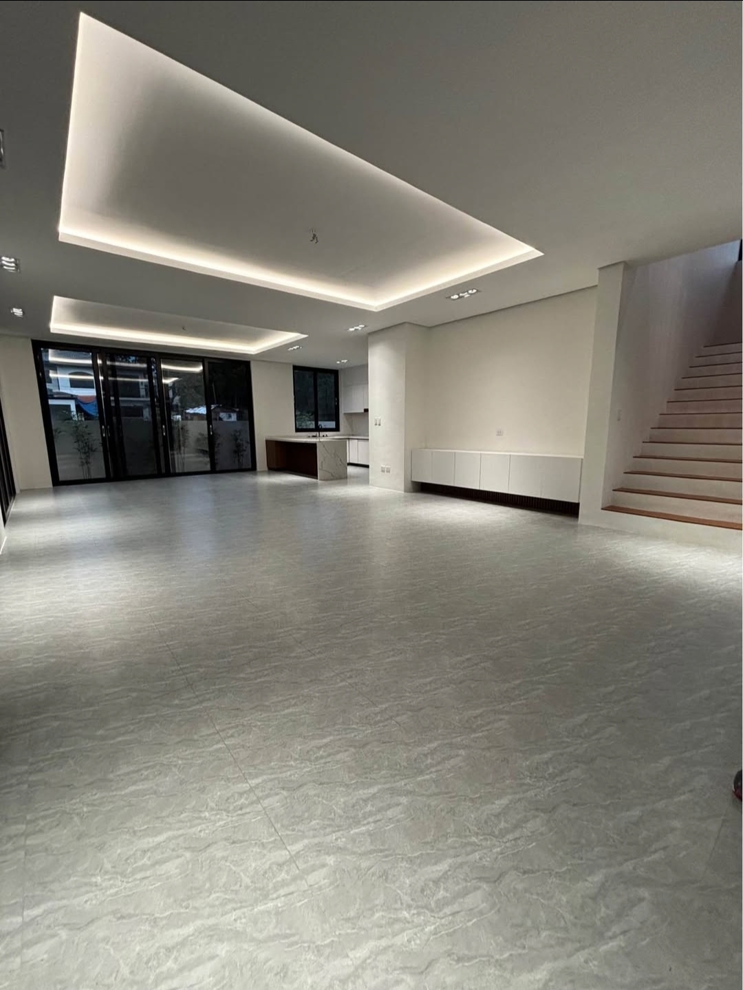 Open-plan living and dining area with cove lighting and full-height glass sliders