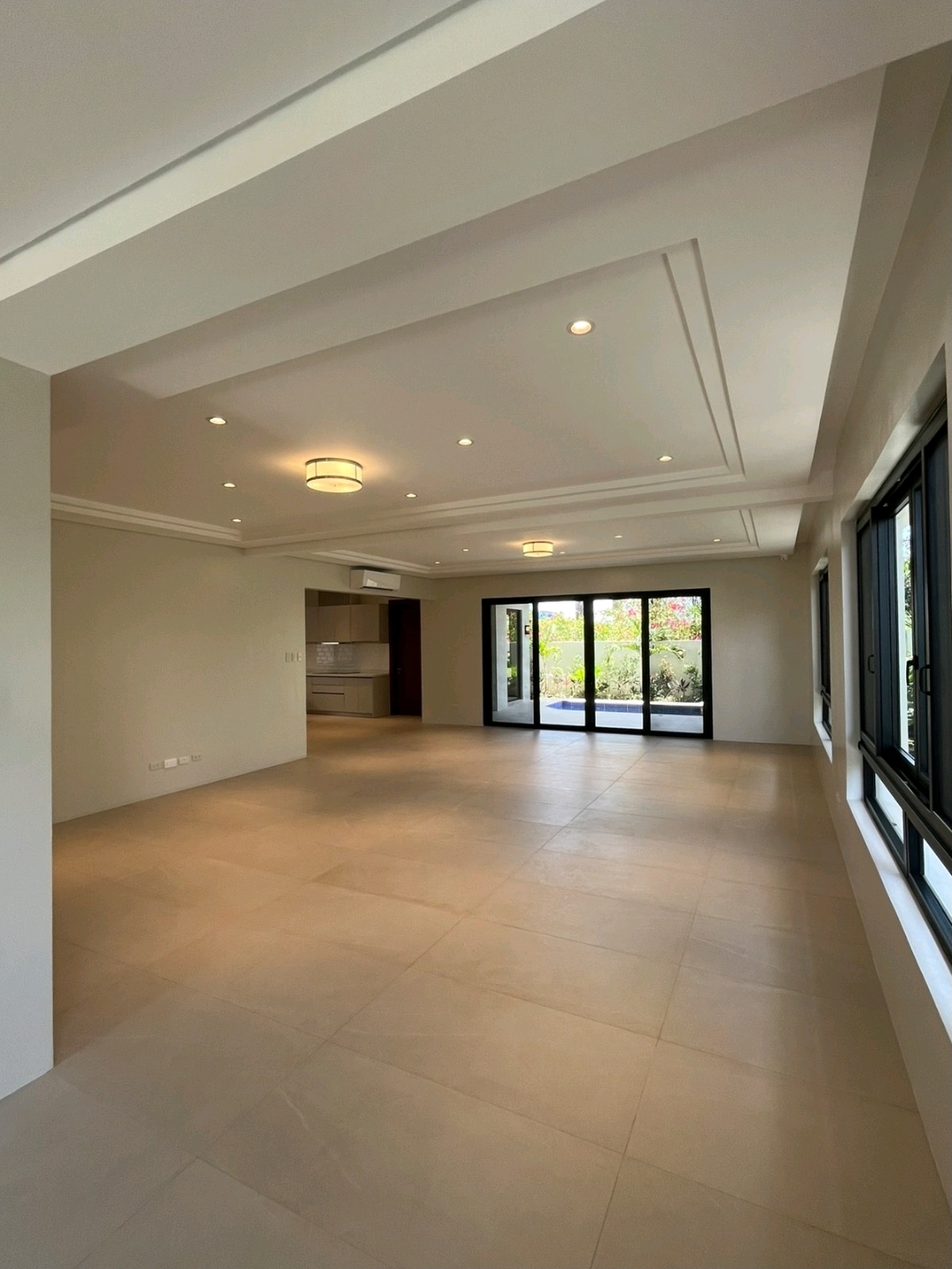 Open living and dining area with cove ceiling and sliding doors to the pool