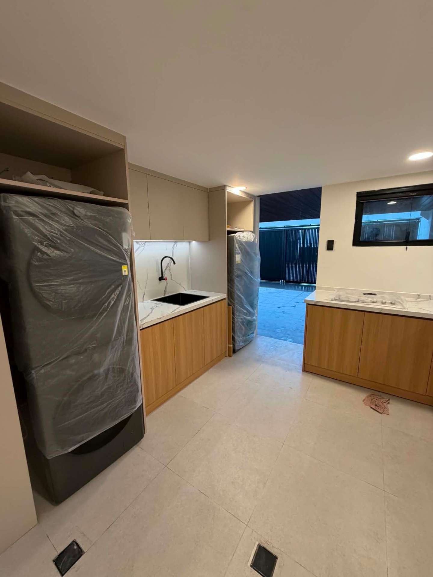 Dirty kitchen with laundry area, marble backsplash and service access to the garage
