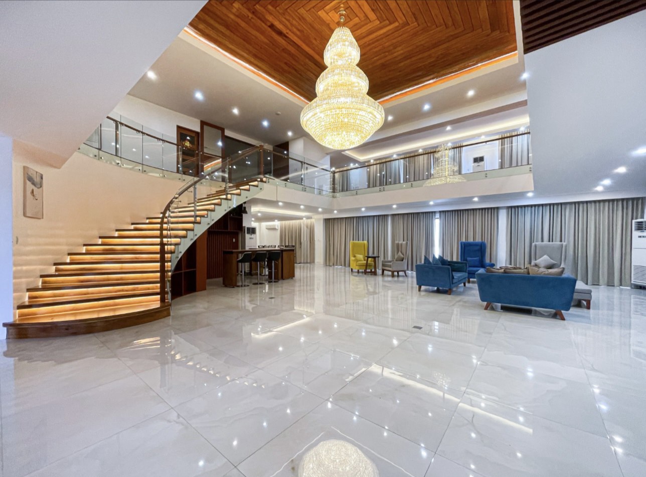 Double-height grand hall with curved lit staircase and crystal chandelier