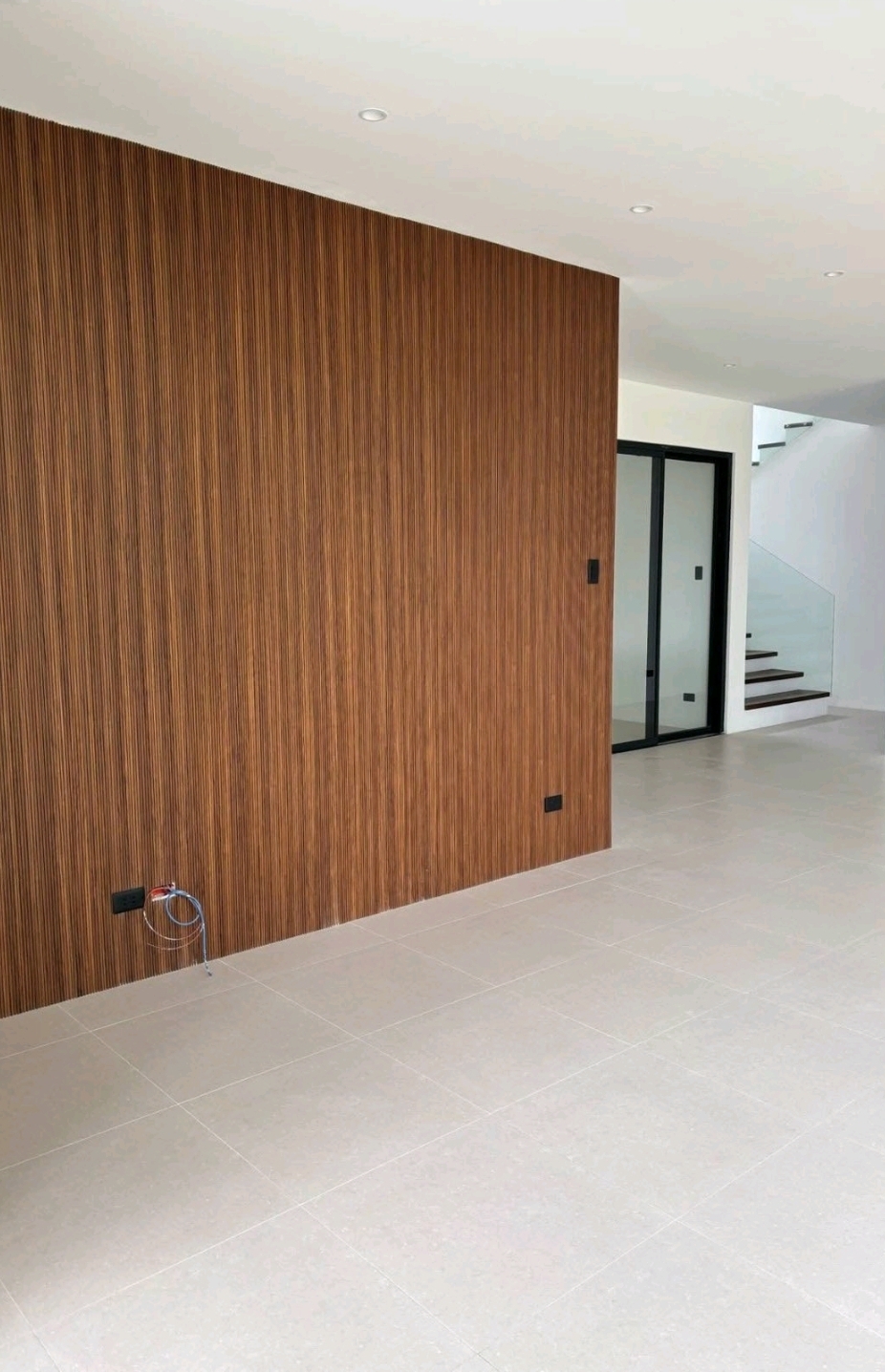Ground floor living area with full-height timber feature wall and glass stair enclosure