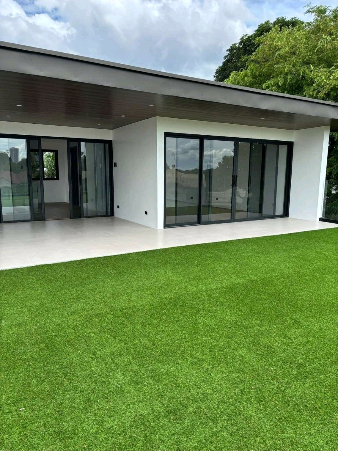 Lanai with sliding glass doors opening onto turfed garden