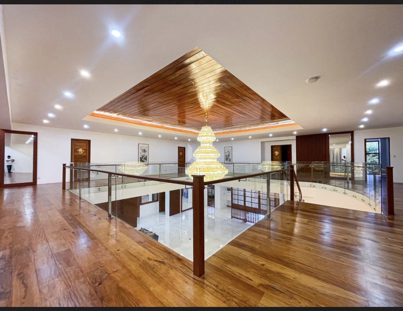 Upper landing with hardwood flooring and glass balustrade around the atrium