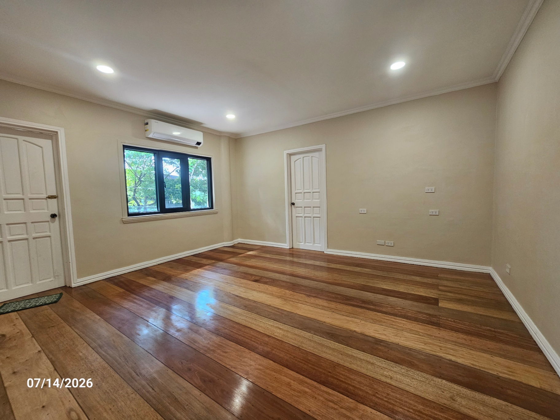 Bedroom with warm wood plank flooring and generous natural light
