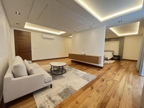 Junior master sitting area with cove-lit ceiling and wood flooring