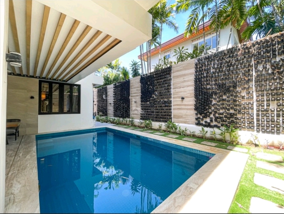 Swimming pool with fountain wall, wood pergola and landscaped side garden