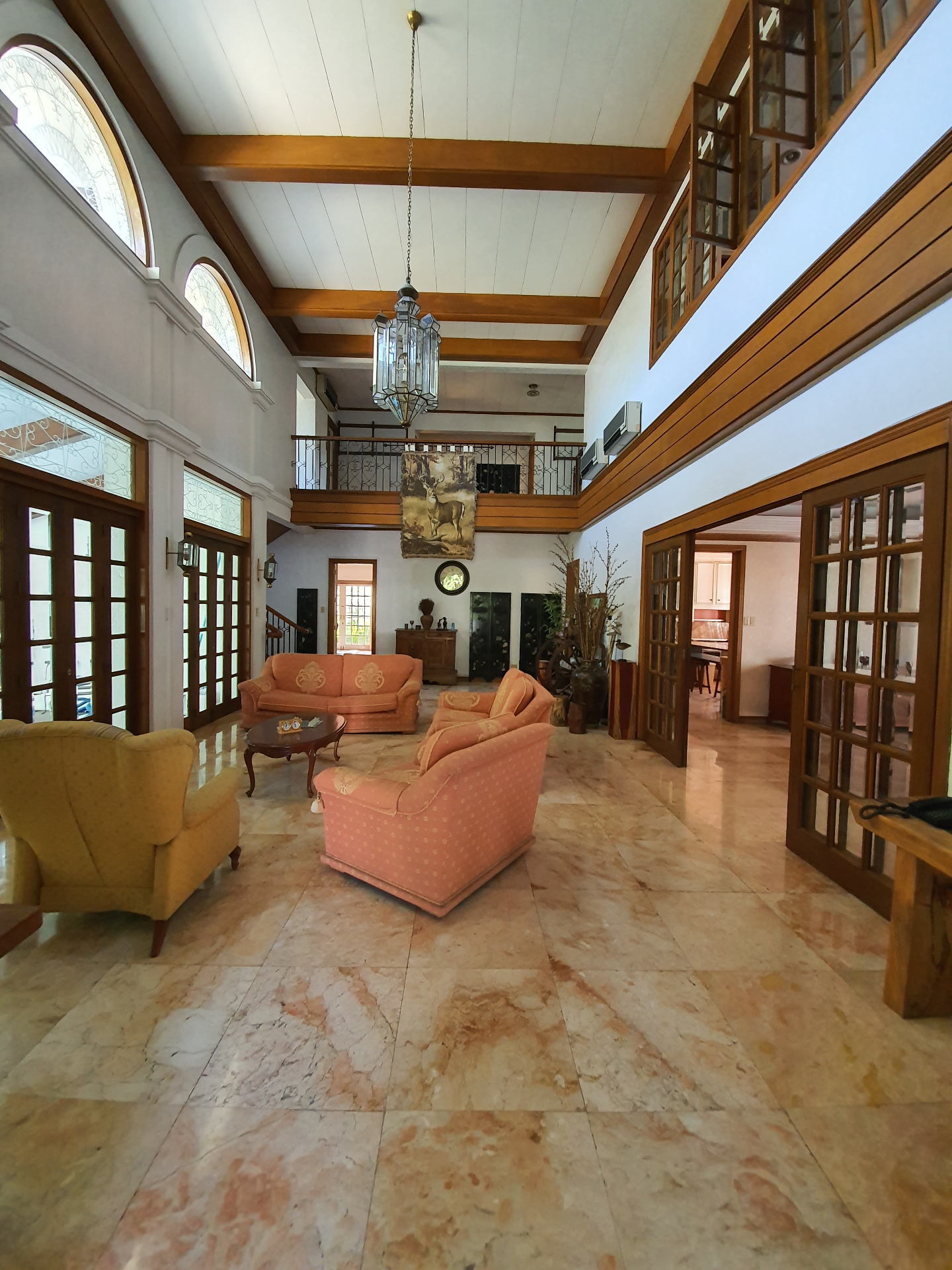 Double-height marble grand hall with timber beams and chandelier