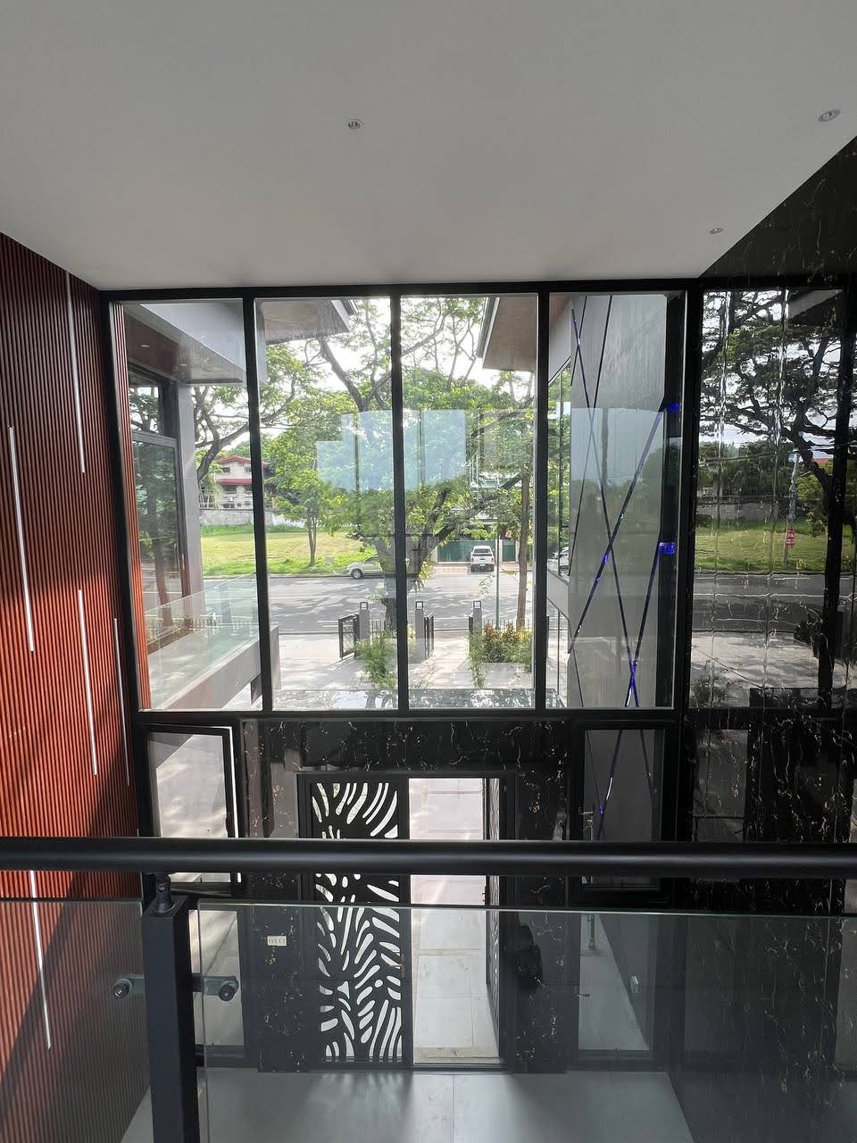 View from inside through full-height windows toward the street