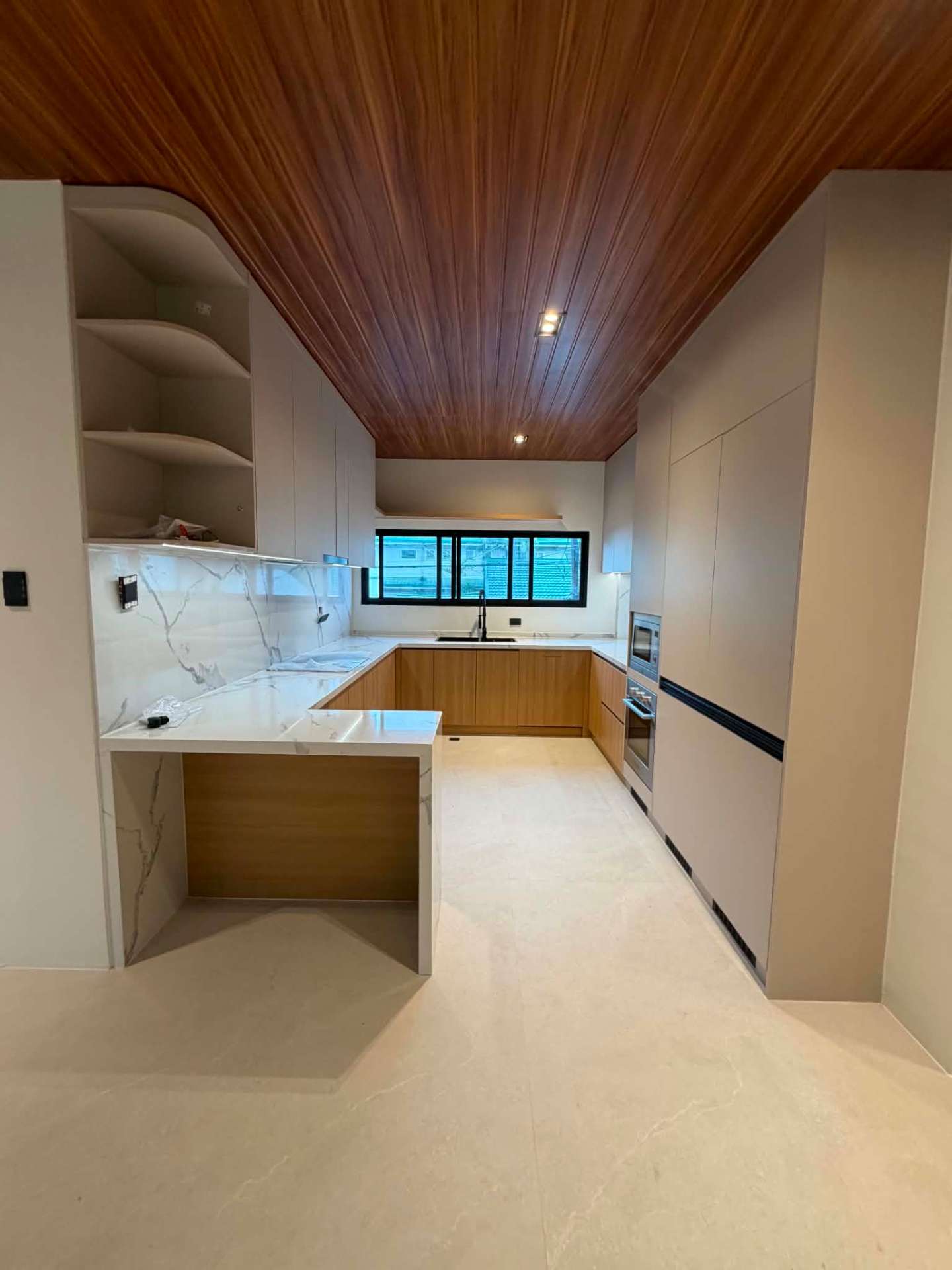 Clean kitchen with marble counters, timber cabinetry and a rich narra plank ceiling