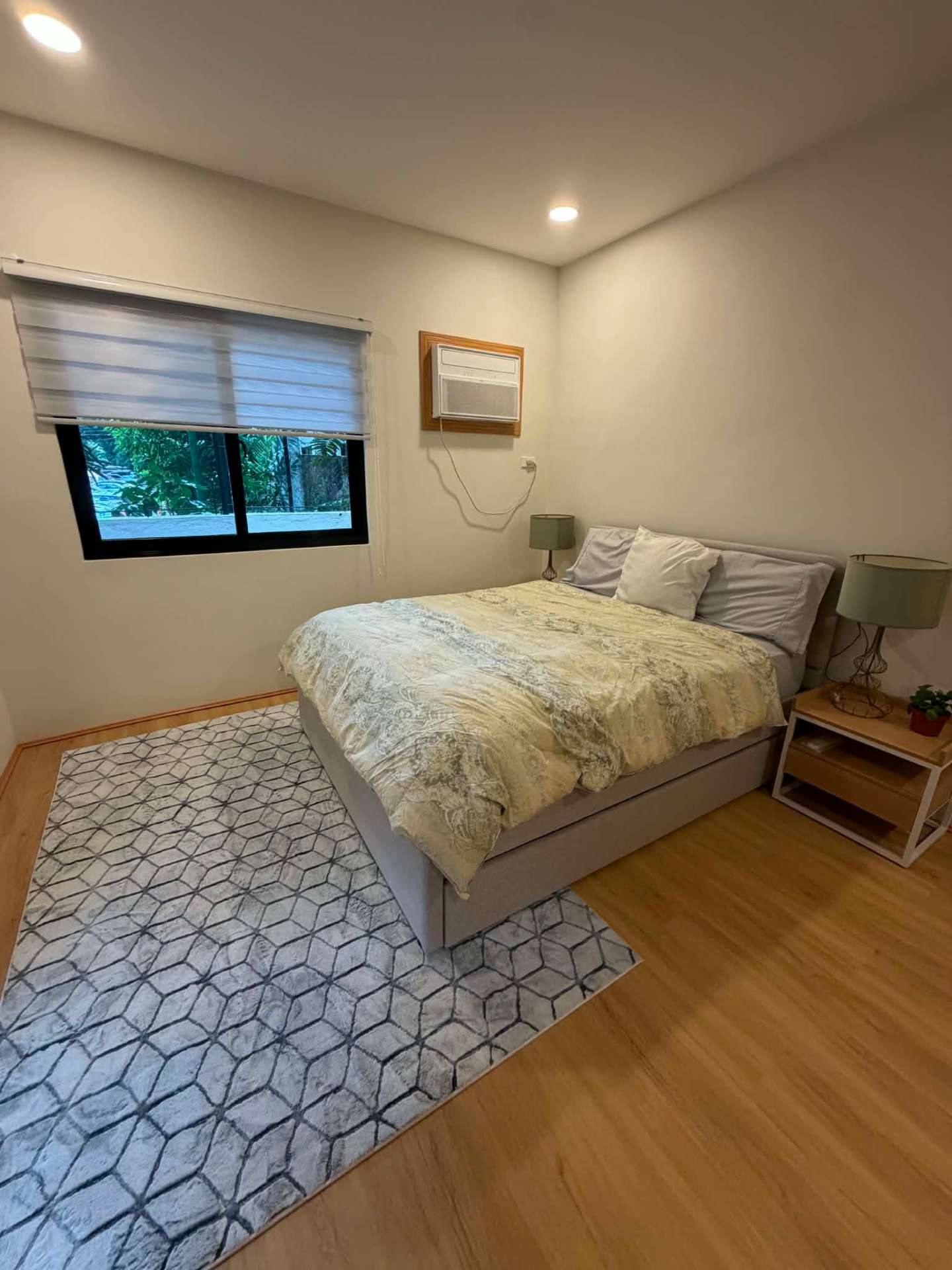 Second bedroom with garden-facing window and wide plank flooring