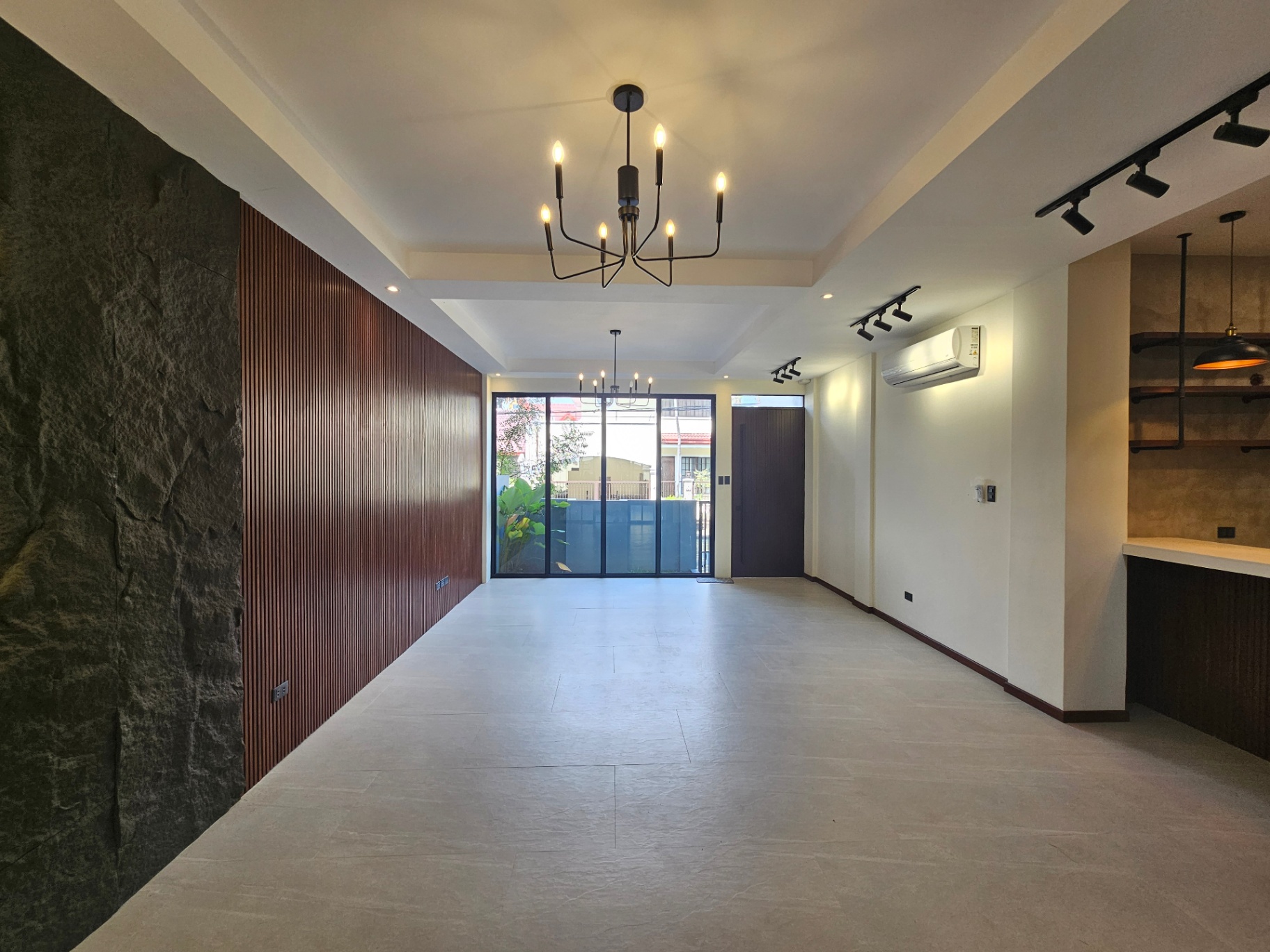 Open living and dining volume with stone feature wall, timber slat panelling and full-height sliders