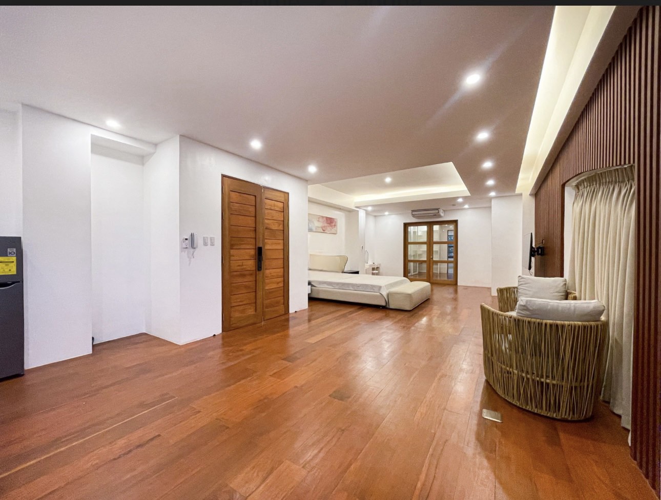 Spacious bedroom suite with hardwood flooring and slatted wood feature wall