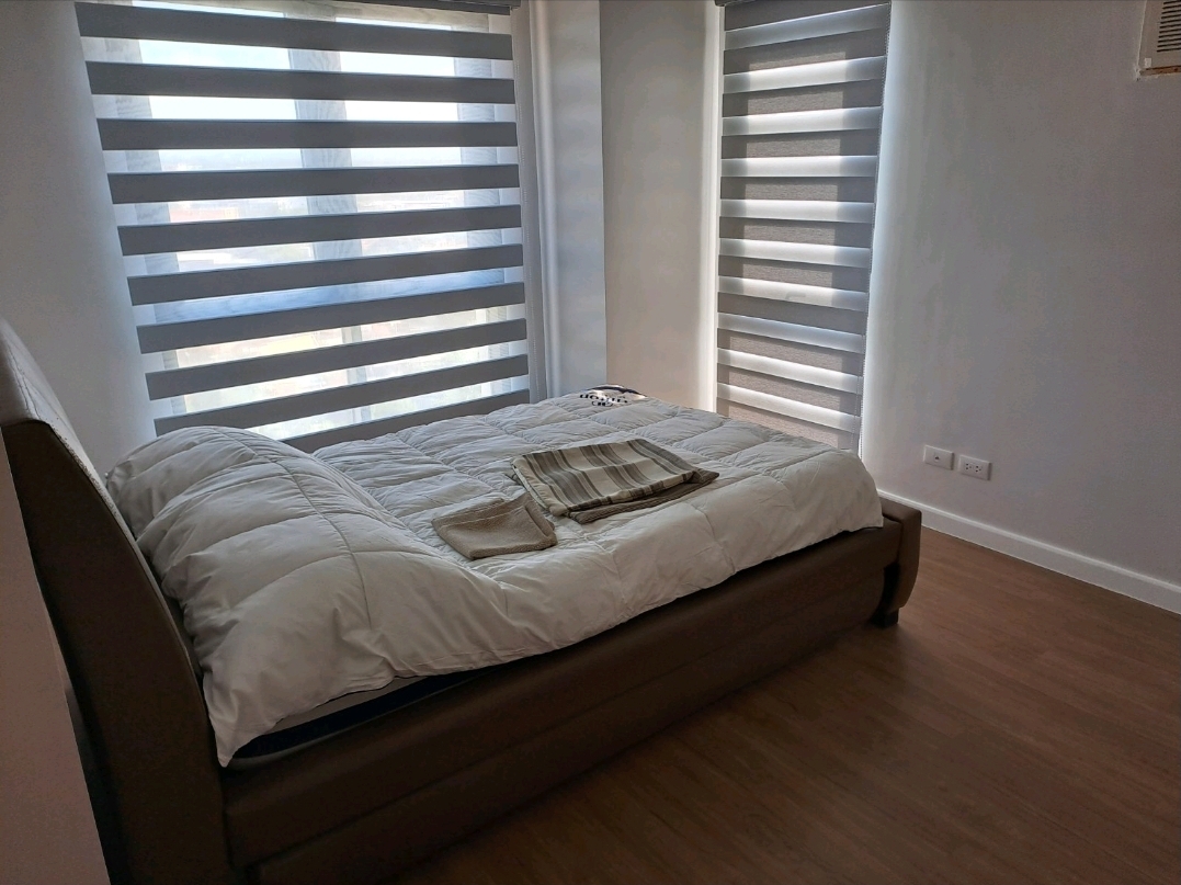 Master bedroom with queen bed and large window in zebra blinds