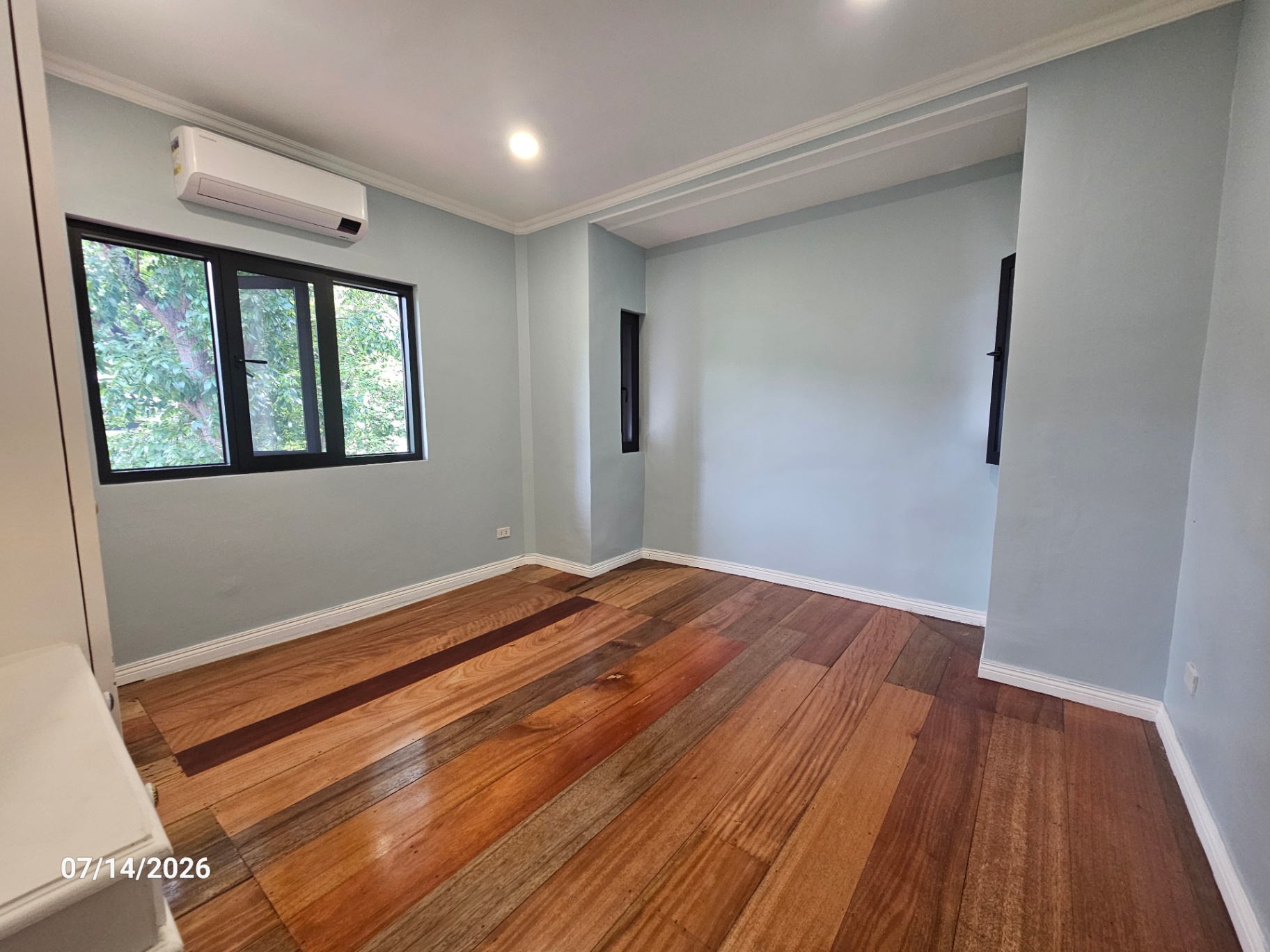 Soft blue bedroom with hardwood floors and an ensuite doorway