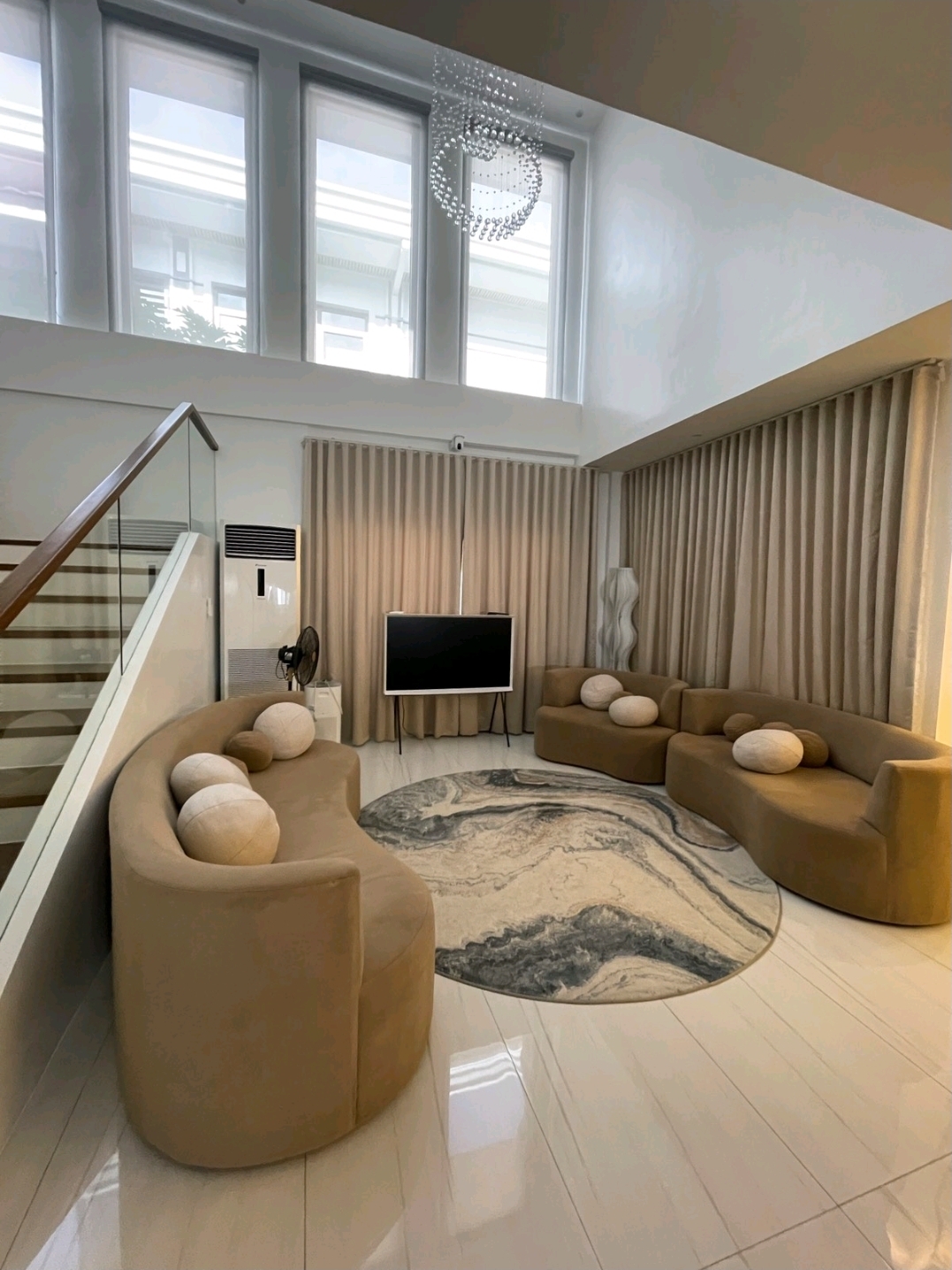 Furnished living room with curved sofas and tall windows