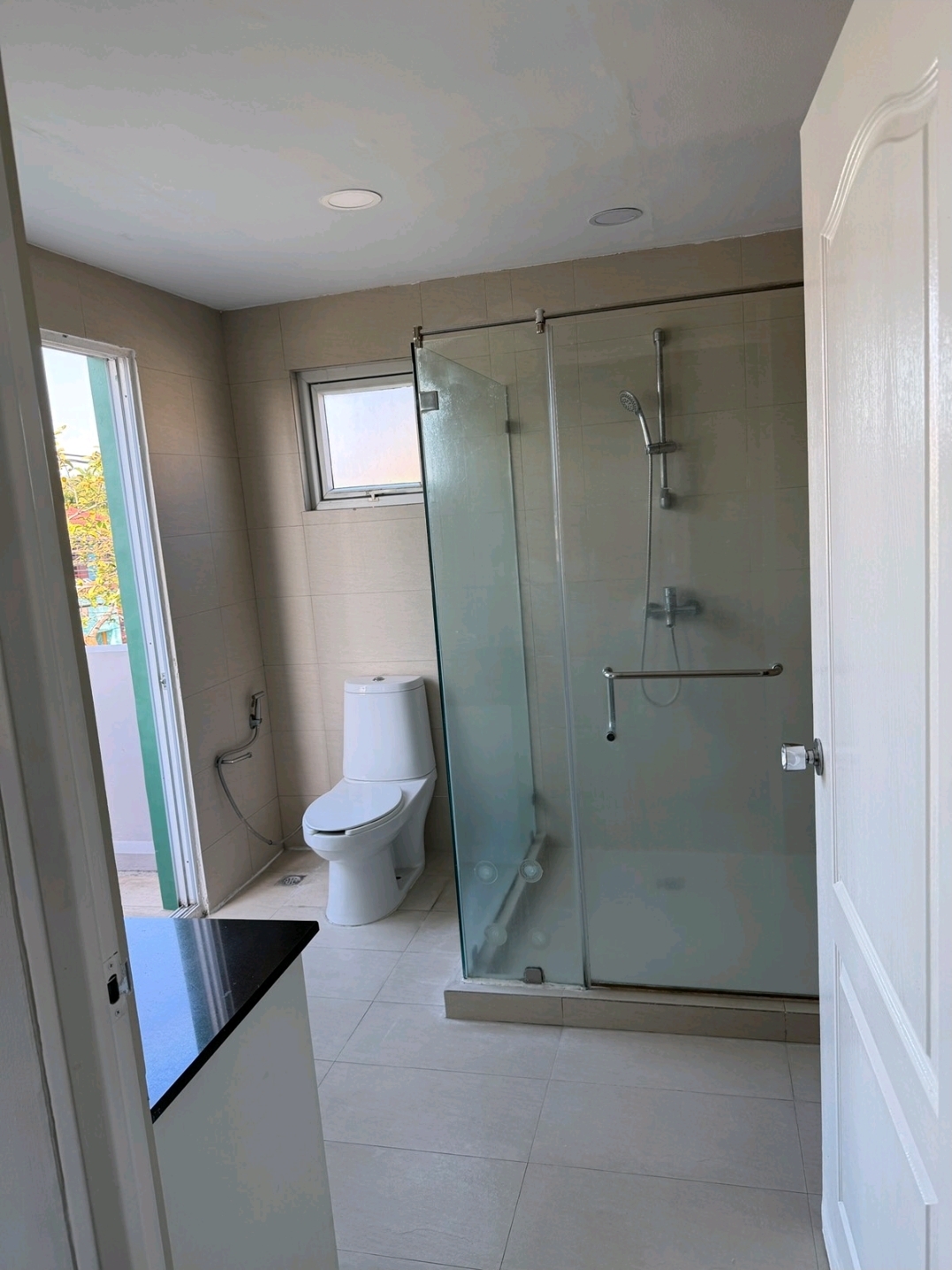 Renovated upstairs bathroom with glass shower enclosure, marble-top vanity and window ventilation