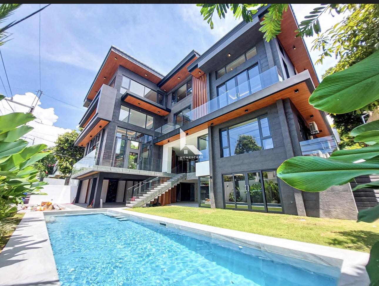 Full-length swimming pool beside the villa’s glass and stone rear elevation
