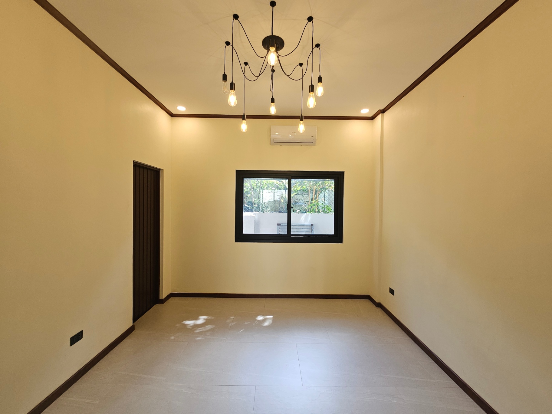 Dining area with filament chandelier and garden-facing window