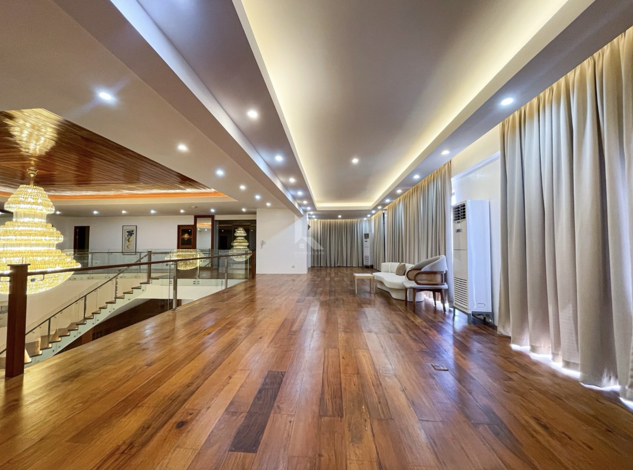 Long upper hall with hardwood floors, cove lighting, and floor-length drapes