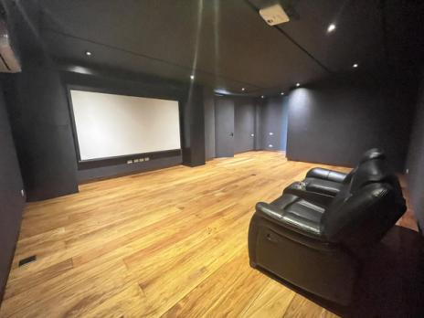Private theater room with projection screen, wood floors and recliners