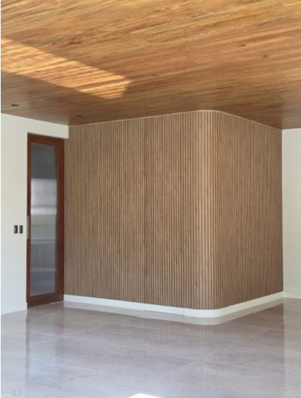 Wood-slat feature wall under a hardwood ceiling