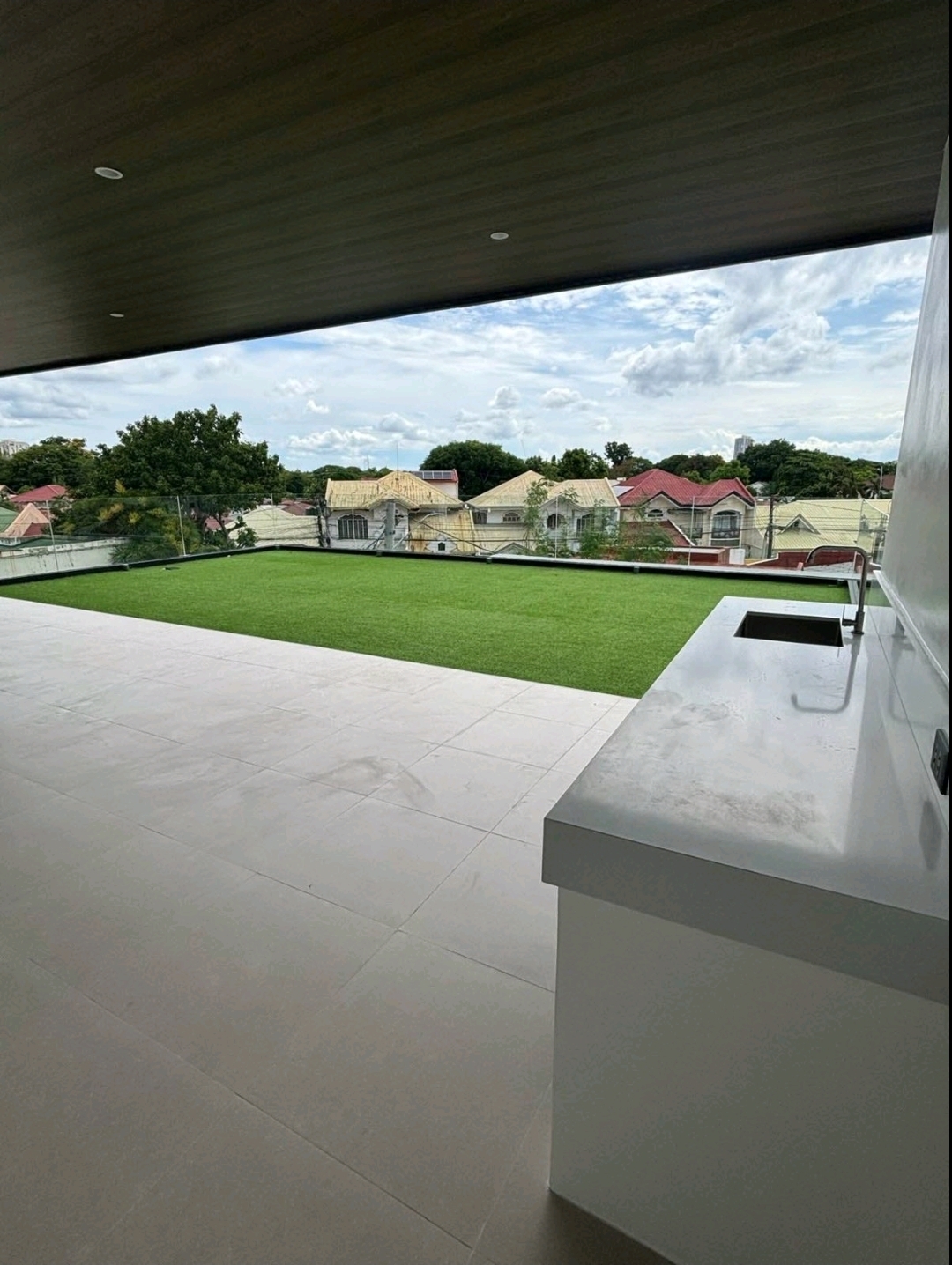 Roof deck kitchen counter beside turfed lounge with village views
