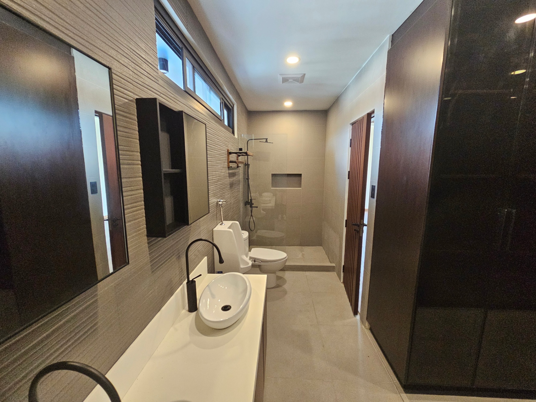 Bathroom with textured tile wall, vessel sink and glass shower partition