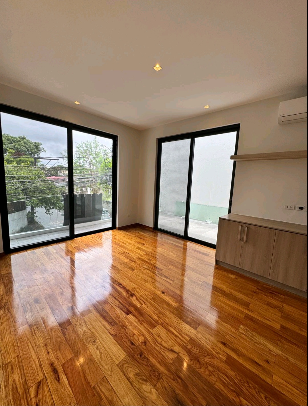 Bedroom with narra hardwood flooring, floor-to-ceiling windows, and built-in cabinetry