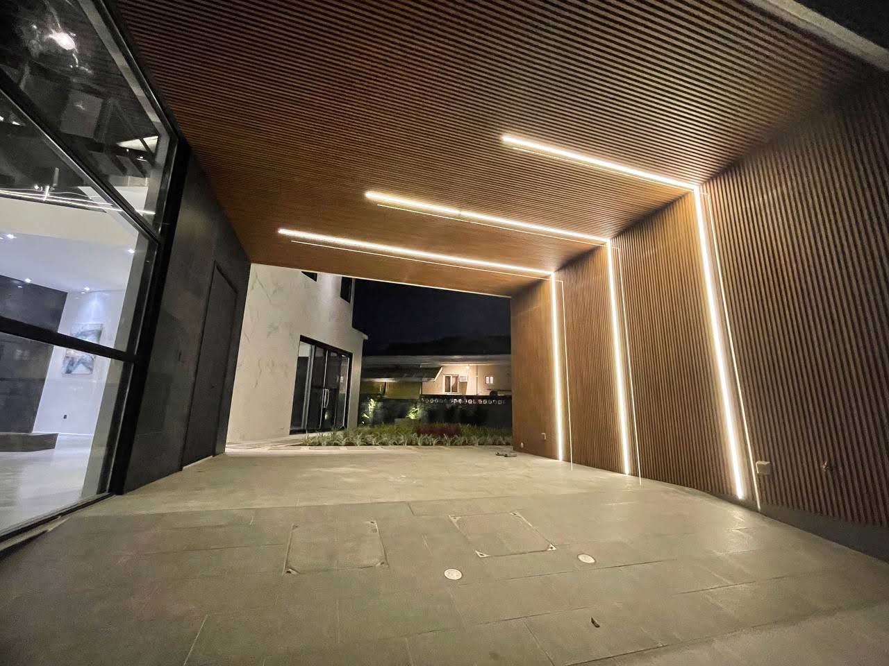 Timber-lined entry and parking court illuminated at night