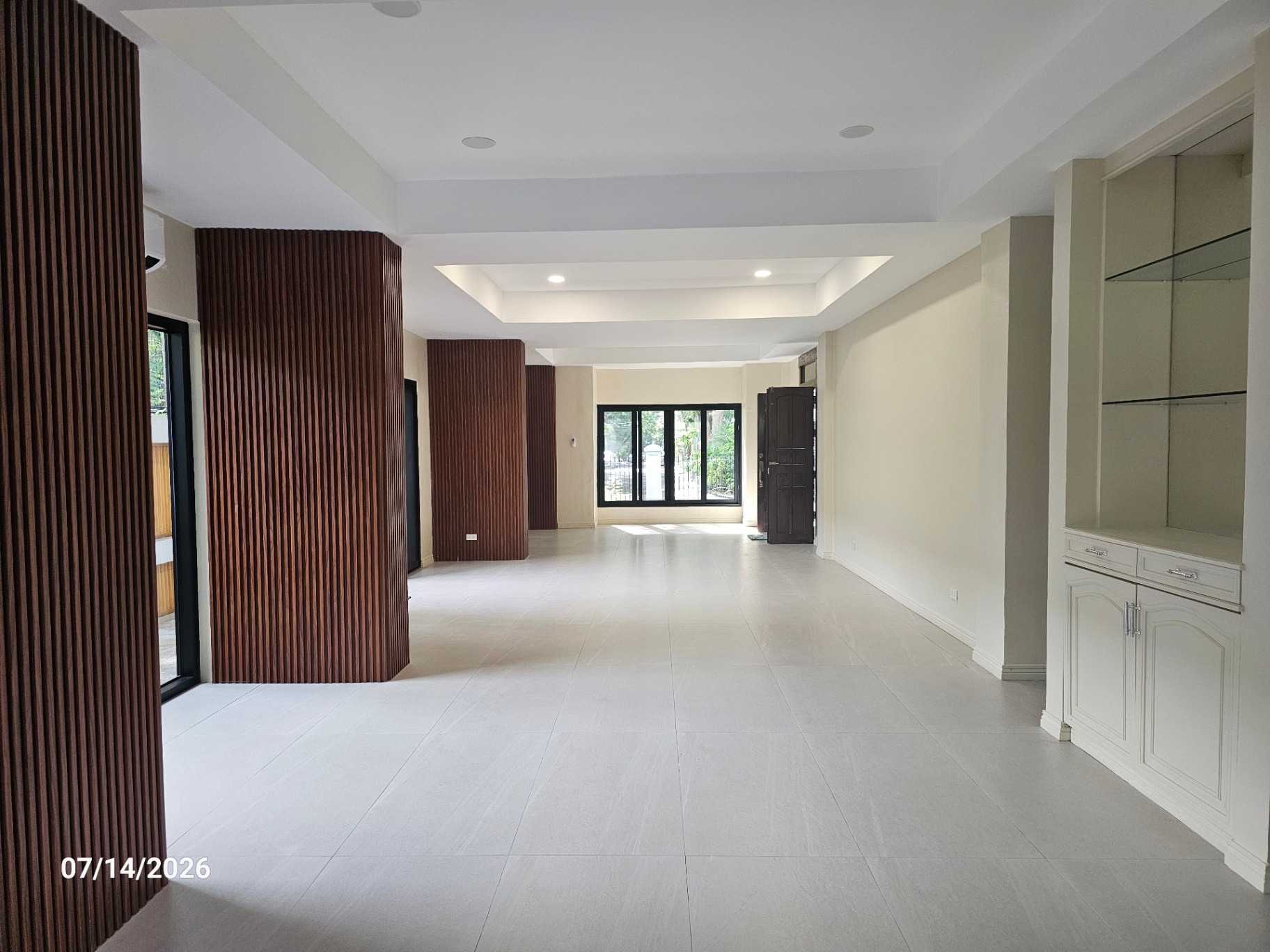 Entry foyer looking toward the main door with wood-slat accents and built-in display cabinet