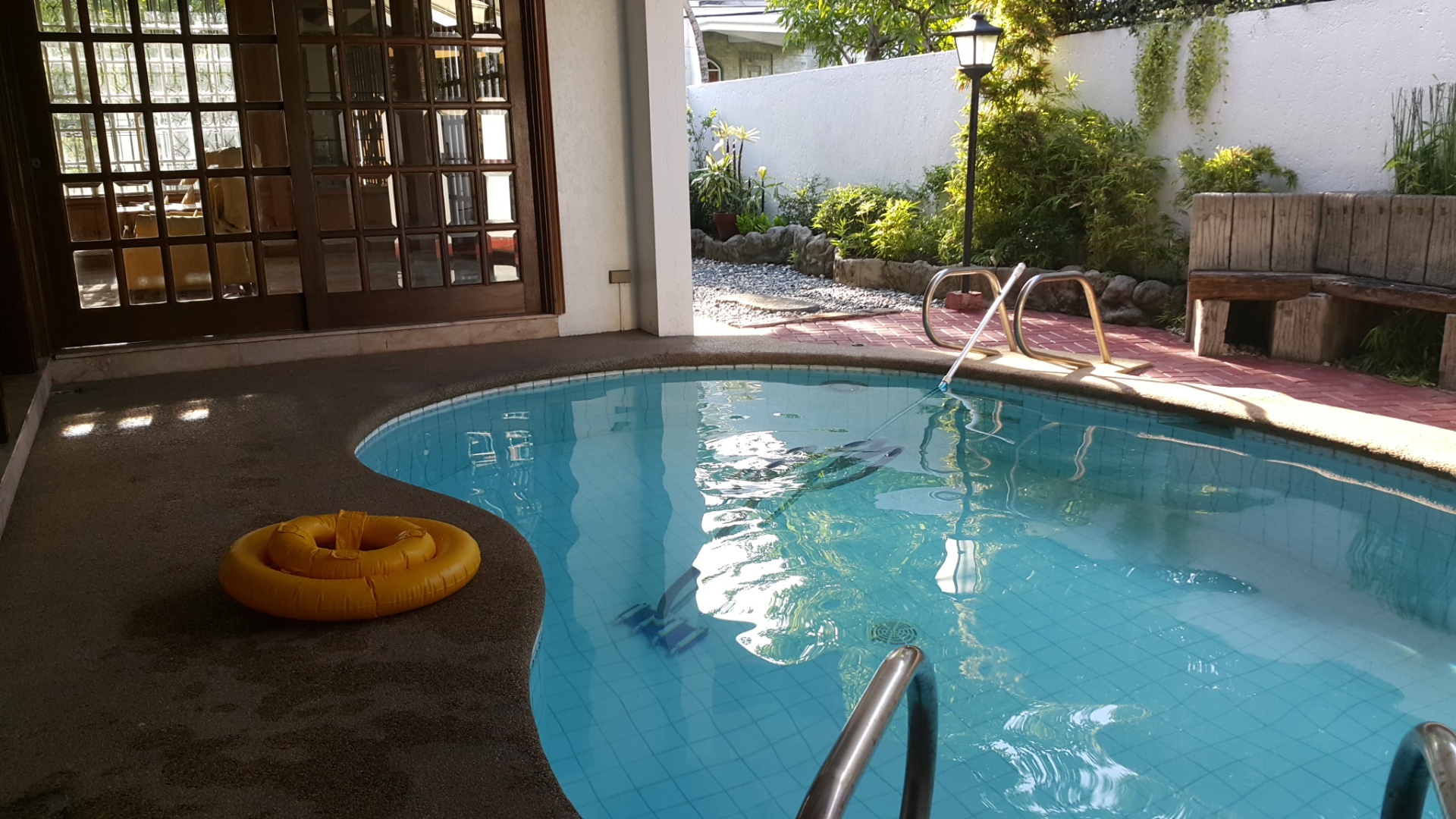 Swimming pool beside the covered lanai and garden wall
