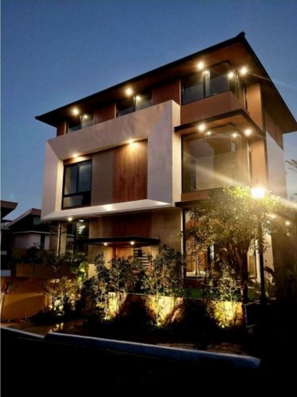 Illuminated modern facade at dusk with landscaped frontage