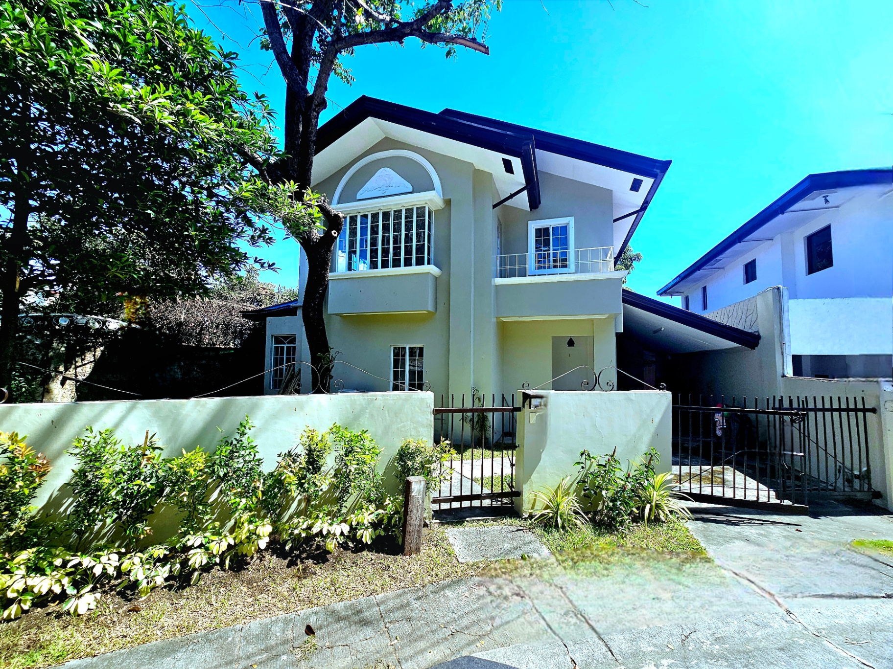 Charming two-storey facade of the Ayala Alabang home with balcony and gated entry