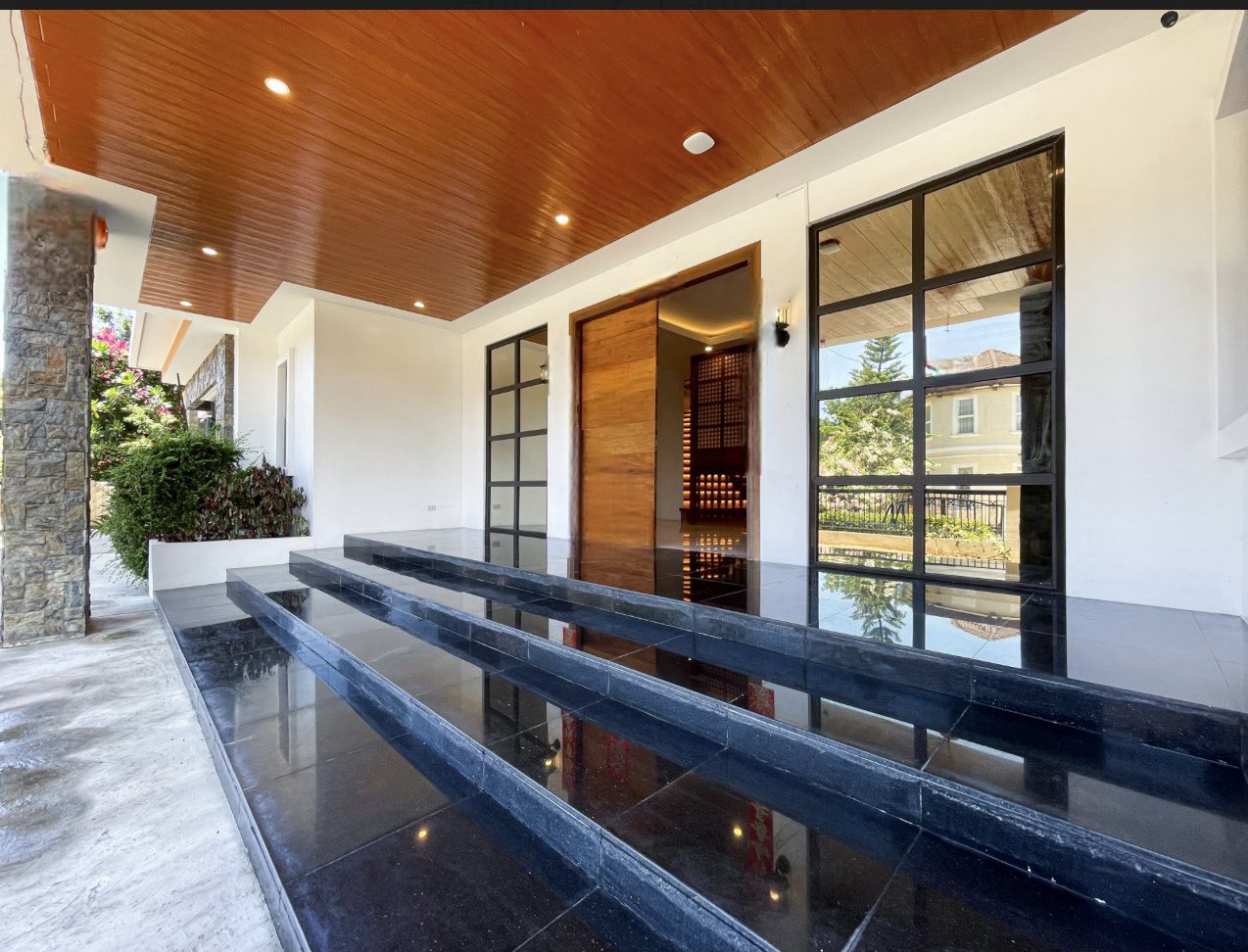 Entry porch with polished black granite steps and tall pivot wood door