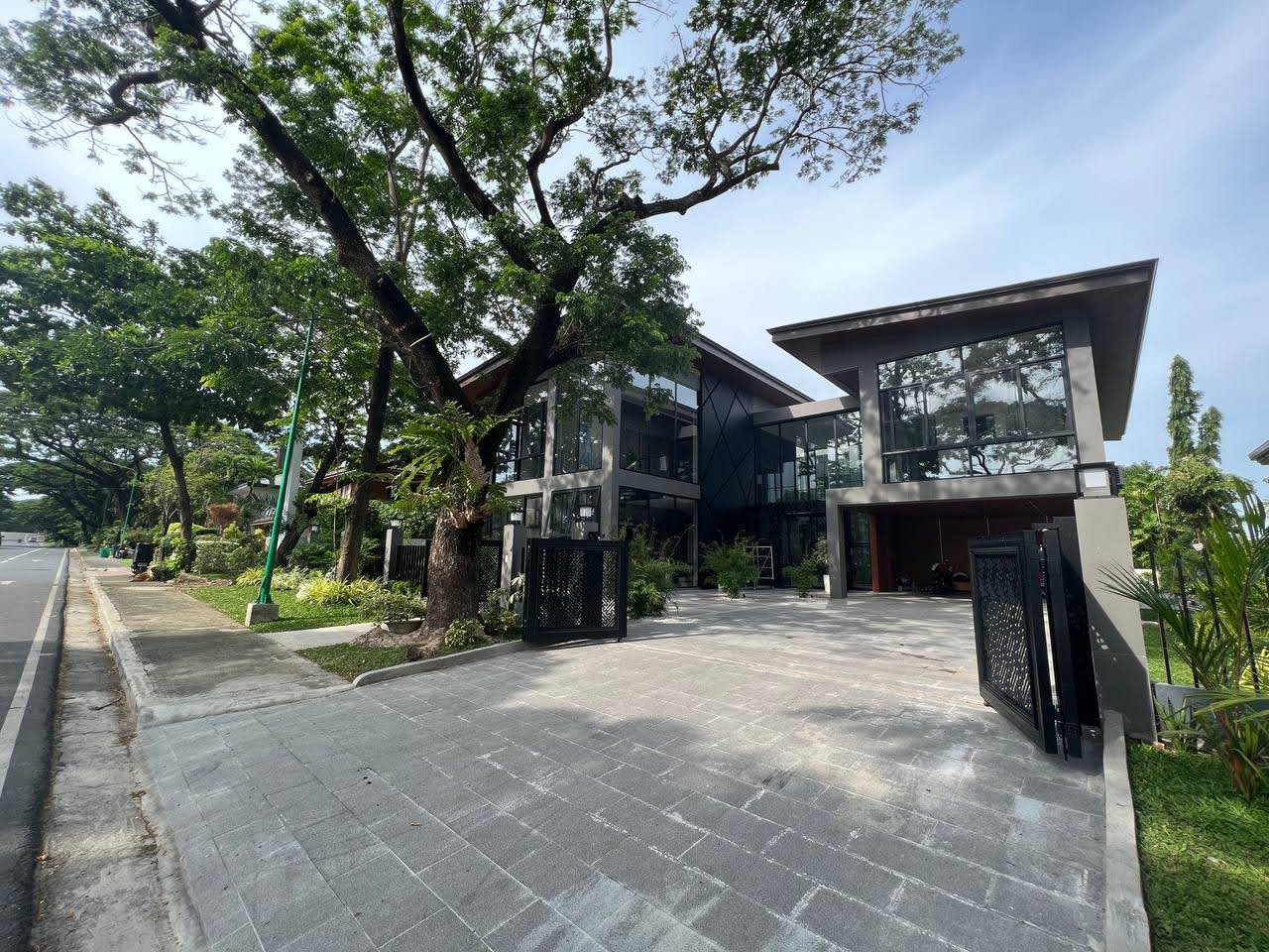Daytime front facade behind a mature tree and black gate