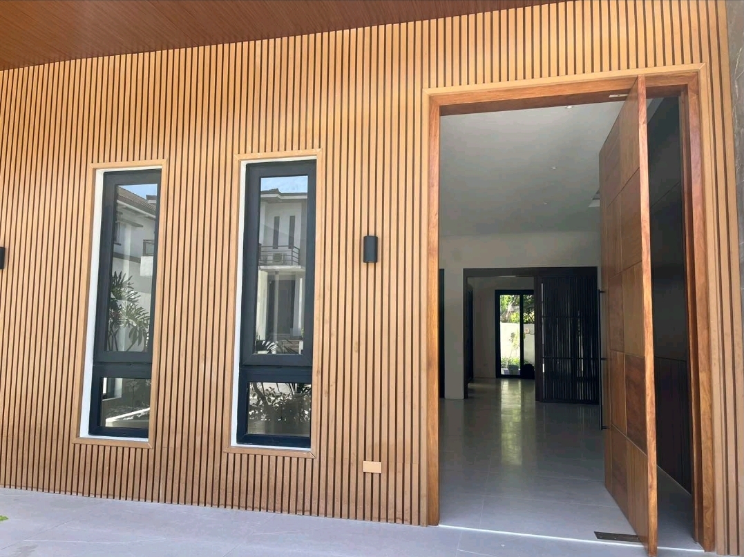 Timber-slatted entry wall with tall pivot door leading to the foyer