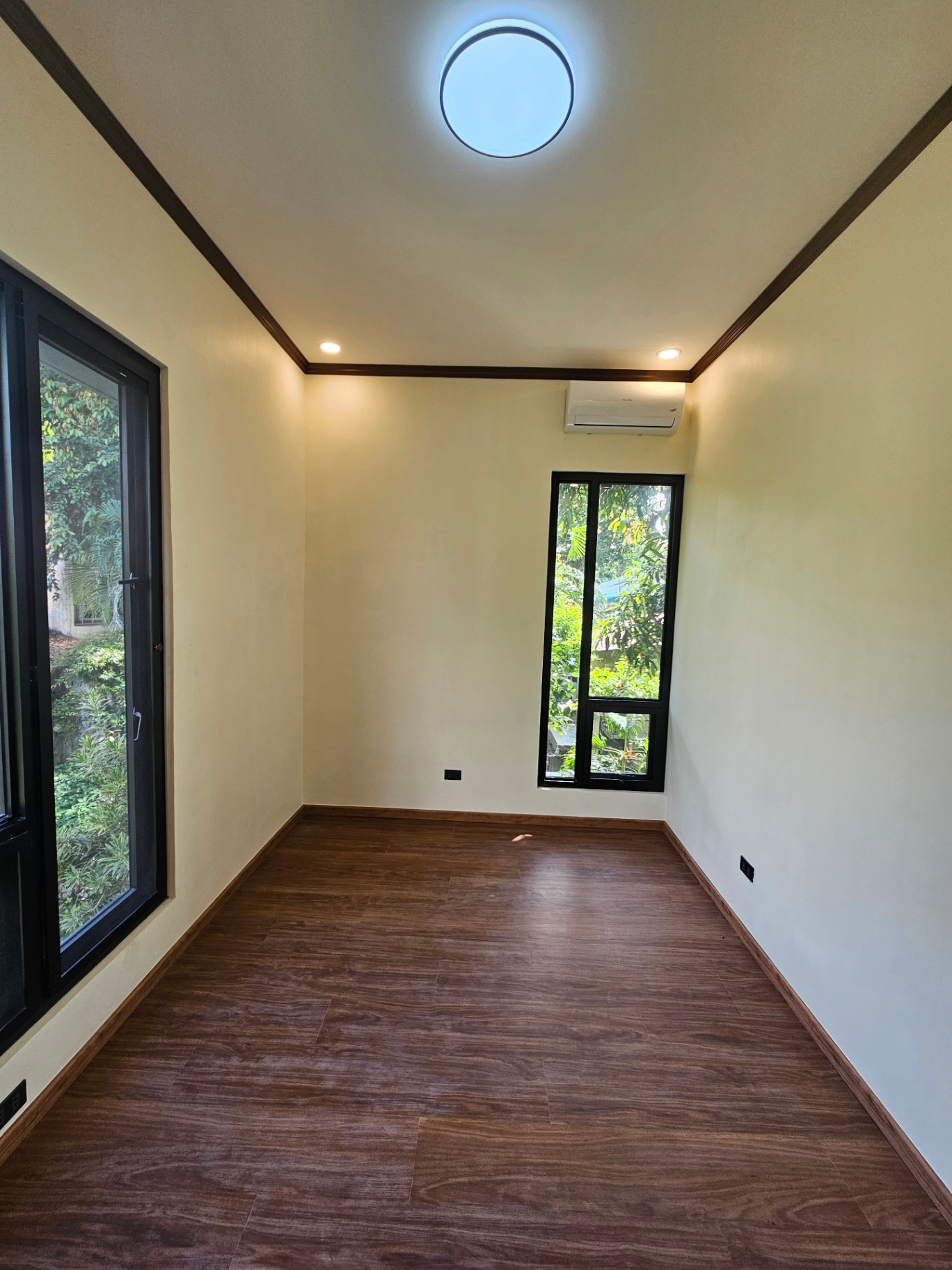 Bedroom with wood-look plank flooring and tall garden-facing windows