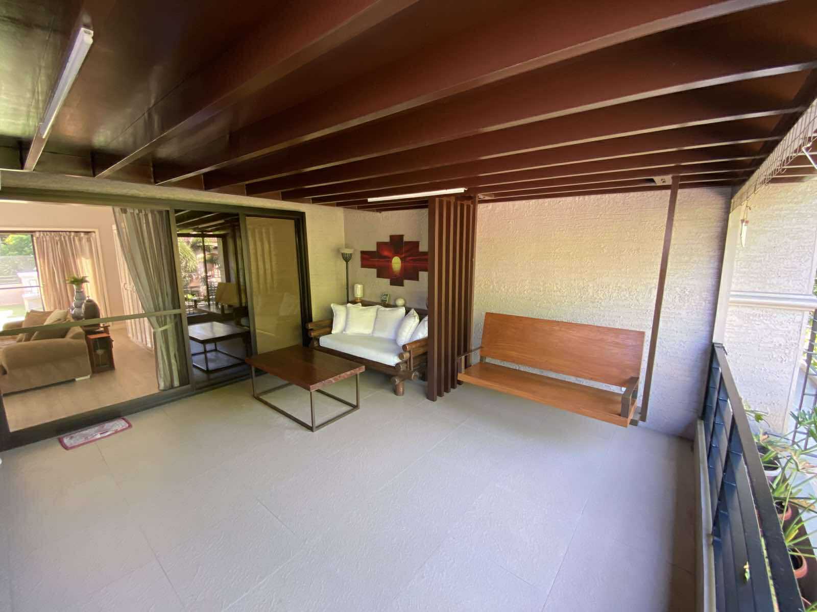 Family hall with timber ceiling beams opening to a balcony lounge