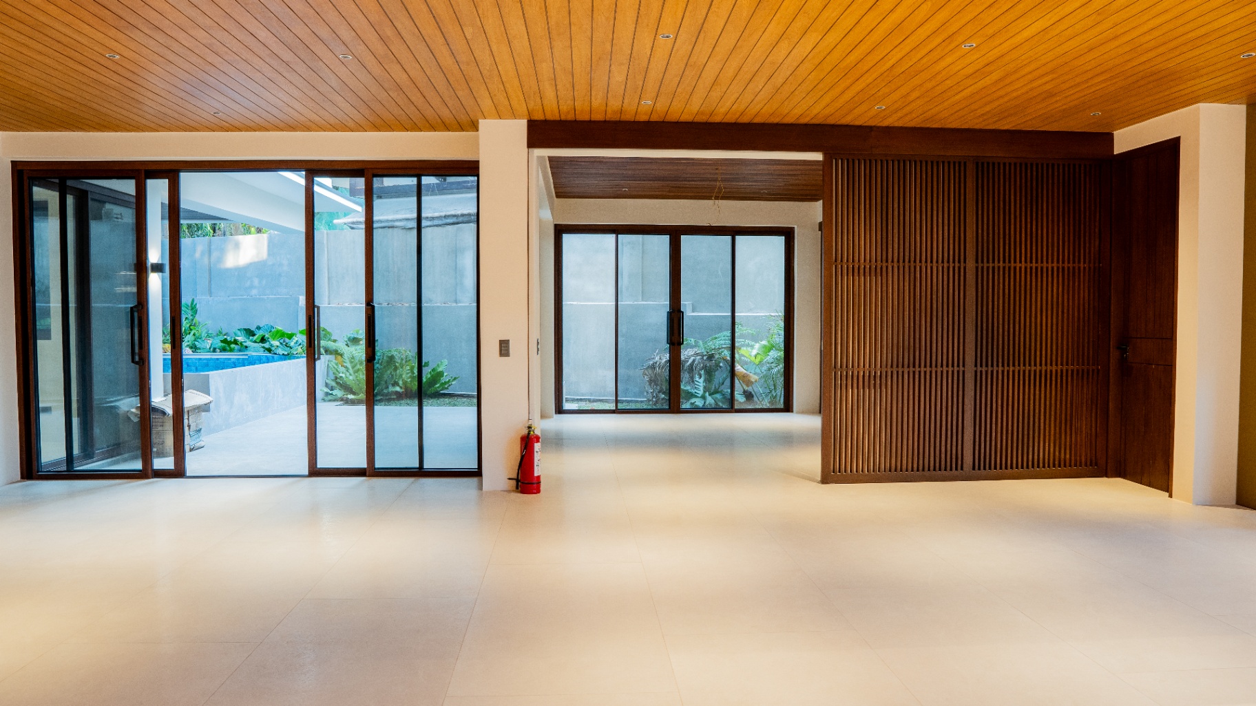 Living area with wood ceiling opening through sliding doors to the pool