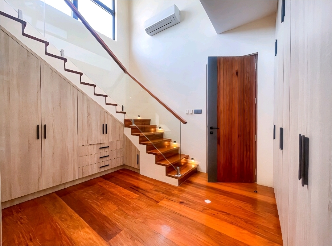 Hardwood staircase with glass balustrade, lit treads and built-in cloakroom joinery