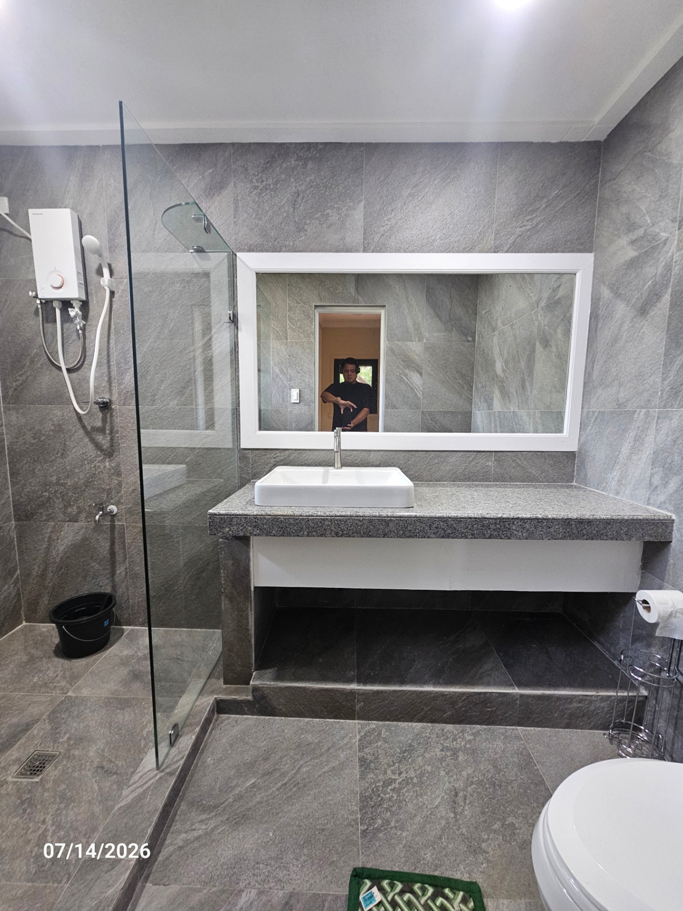 Second renovated bathroom with grey stone tile, glass shower enclosure, and floating vanity