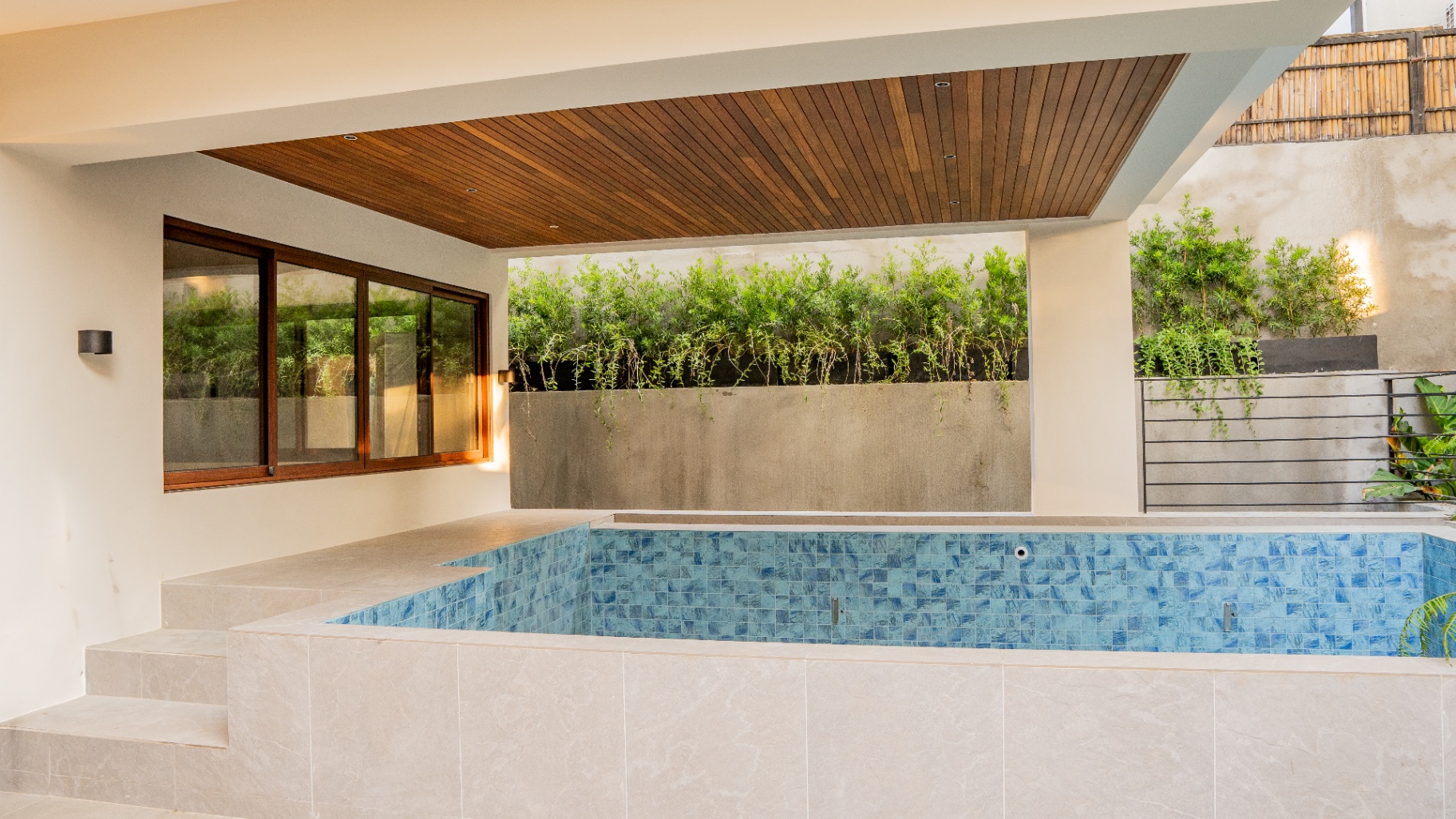 Covered swimming pool framed by planters and a slatted wood ceiling