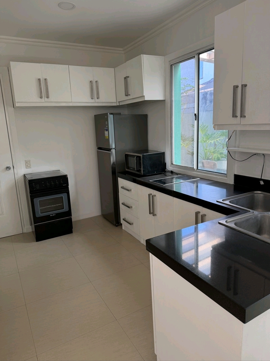 Fully equipped kitchen with marble-look black counters, induction hob, oven, microwave and ample white cabinetry
