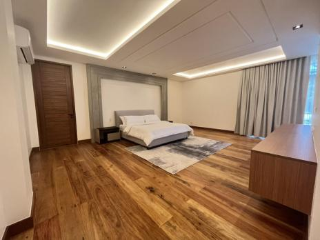 Master bedroom with wide-plank wood floors and recessed cove lighting